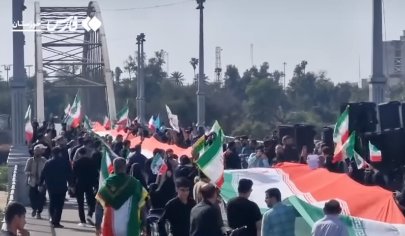 People marching crossed a span holding ample Iranian flags during a protest