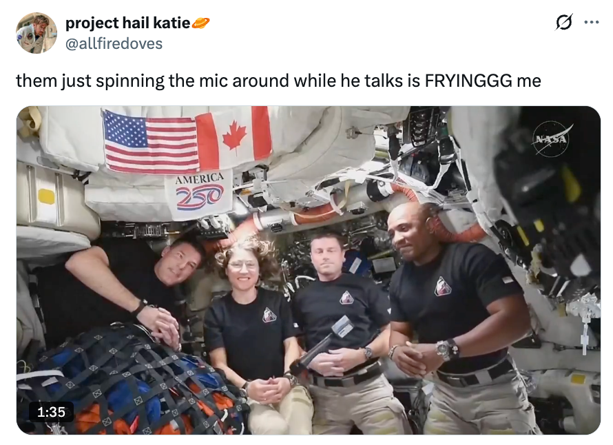 Astronauter inne i romfartøy, smilende i uniformer, et USA og Canada flagg synlig. Tekst: "America 250" og 