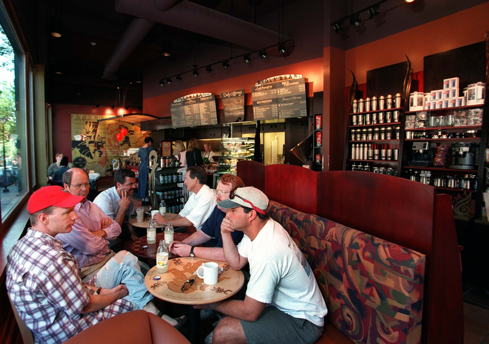 People sitting astatine a java store table, engaged successful conversation, with shelves of java products successful the background