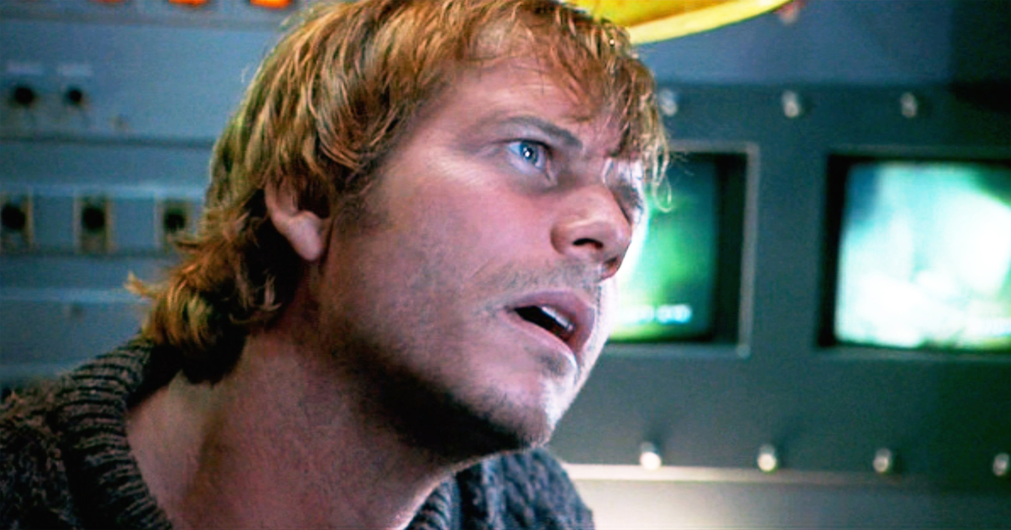 Person with short hair looking intently at a screen in a control room setting