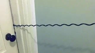 A doorway with a long, twisty cord attached to the doorknob, stretching to the wall, resembling a originative DIY doorway closure oregon information lock