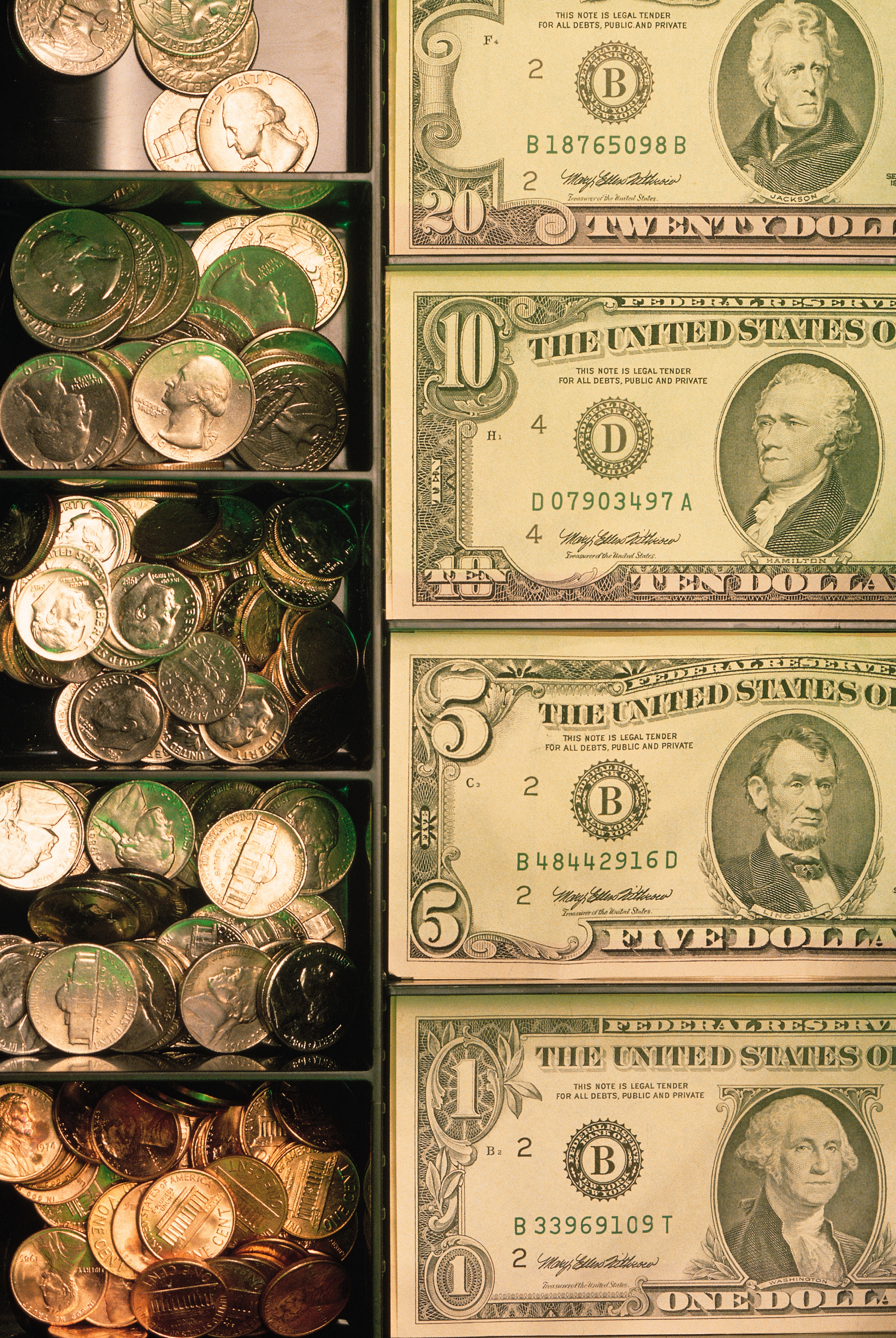 Assorted coins and U.S. dollar bills organized successful a currency drawer