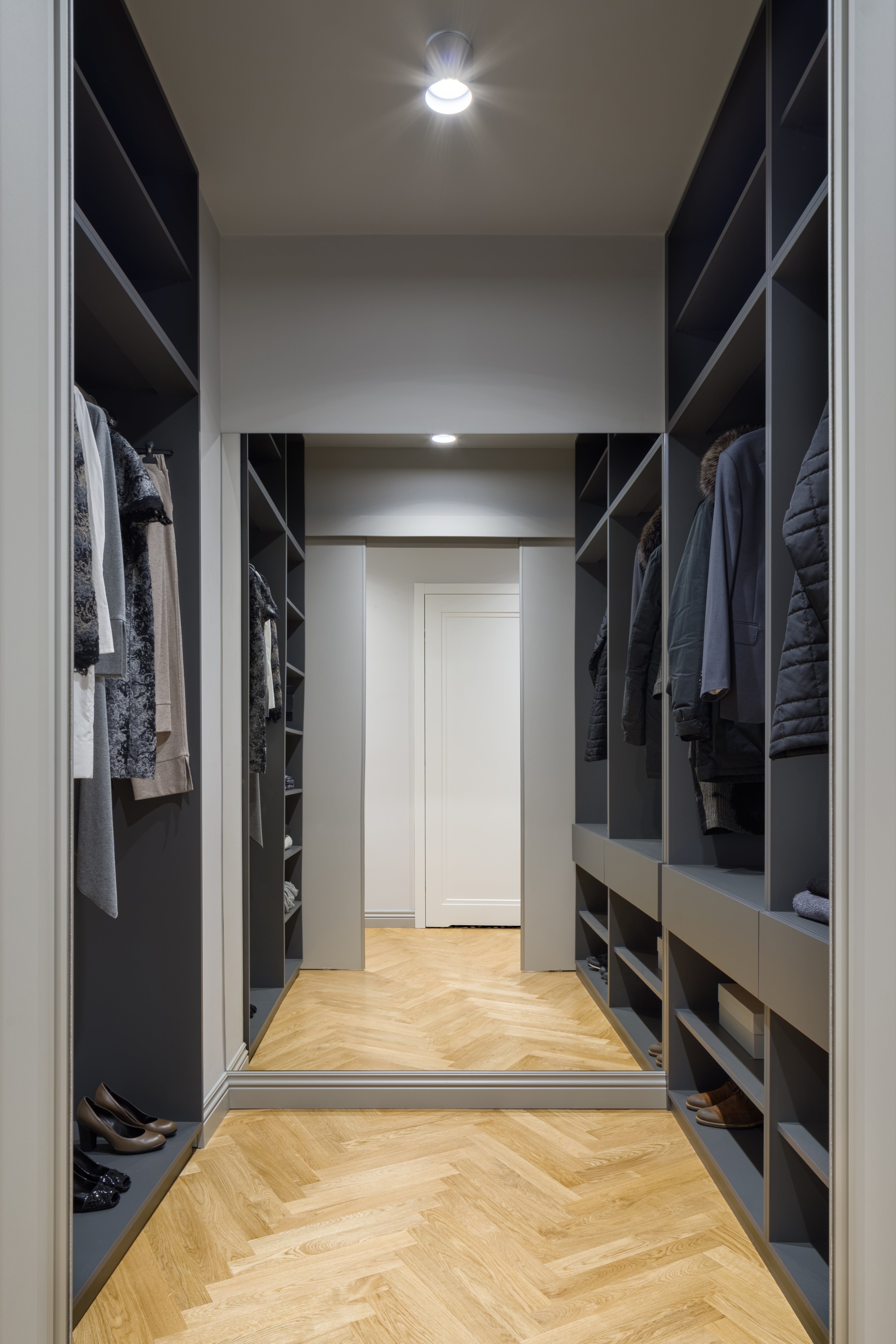 Spacious walk-in closet with various clothes and shoes neatly organized on shelves and hangers, reflecting a tidy and modern design