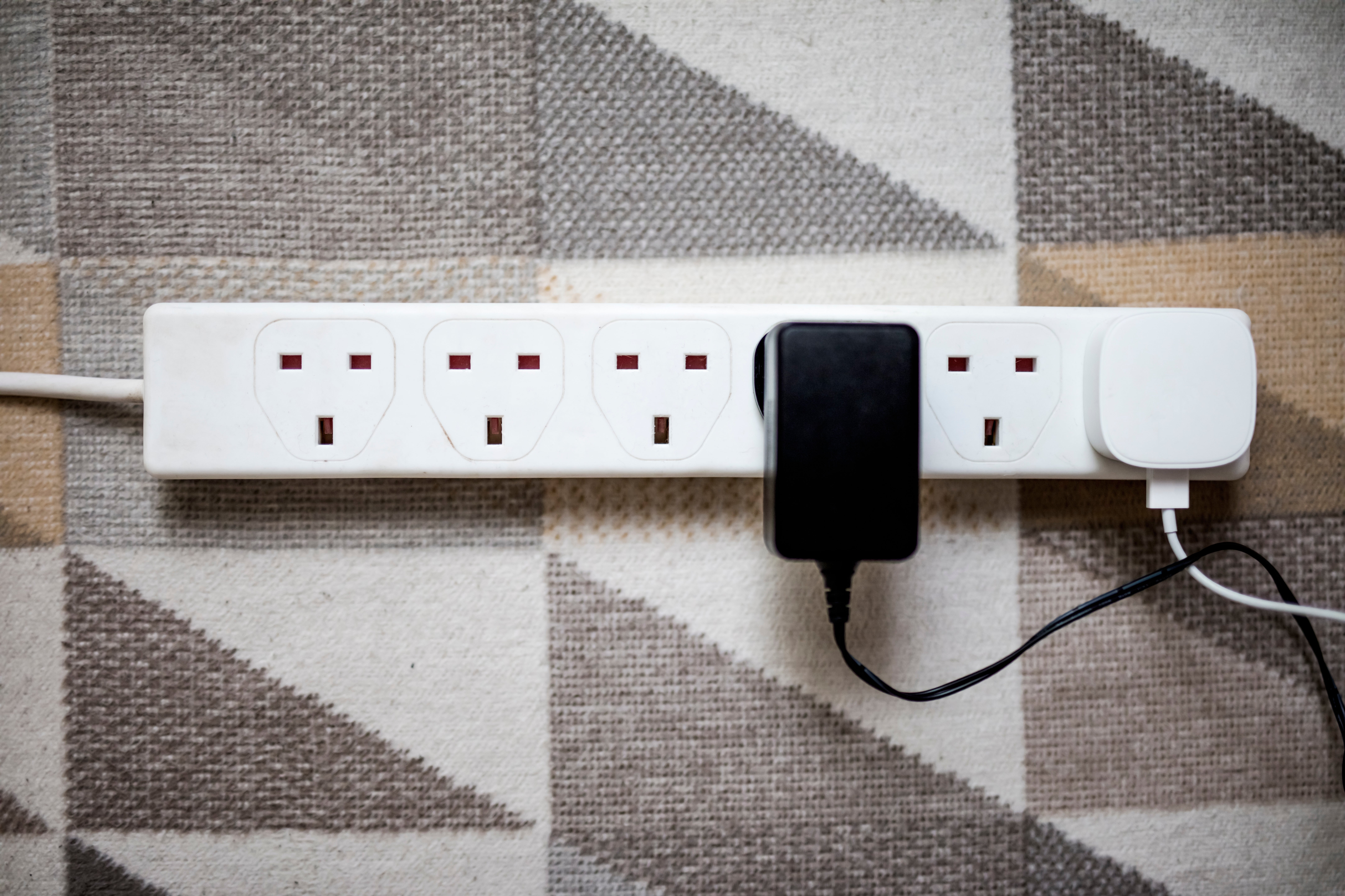 Power strip with multiple plugs connected, resting on a geometric-patterned surface