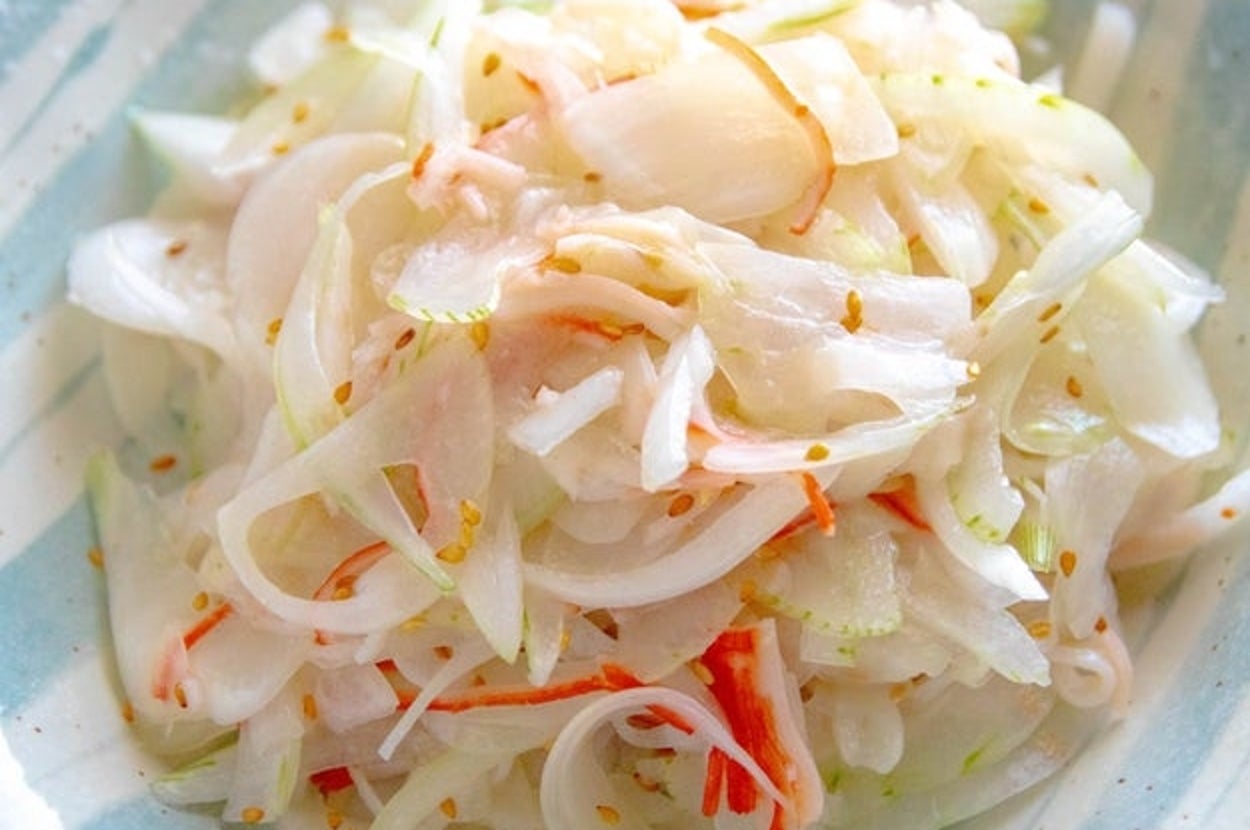 薄切りの玉ねぎと他の野菜が和えられた、さっぱりとしたサラダが器に盛られている。