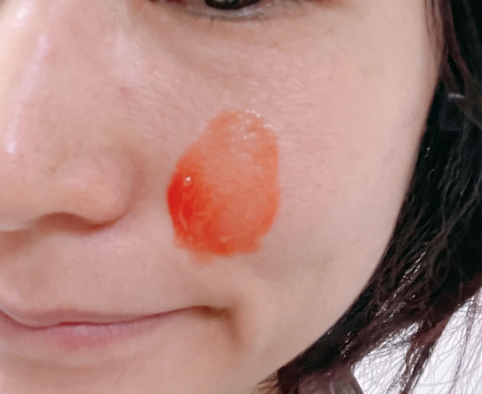 頬にサーモンピンクのジェルのついた人物のクローズアップ。表情は穏やかです。