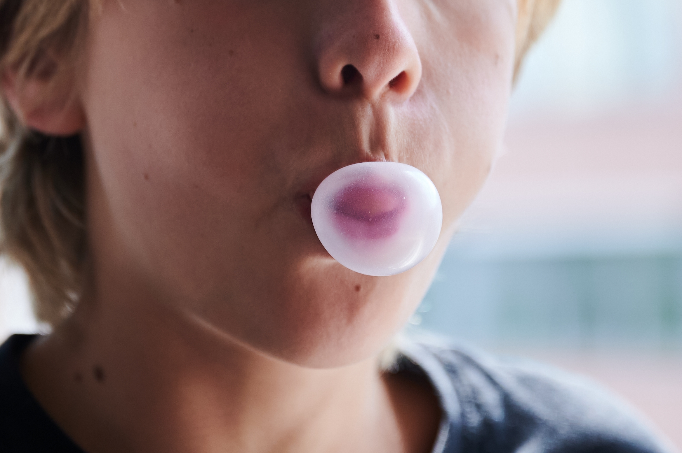 Person blowing a bubble with gum, focusing connected  the rima  area