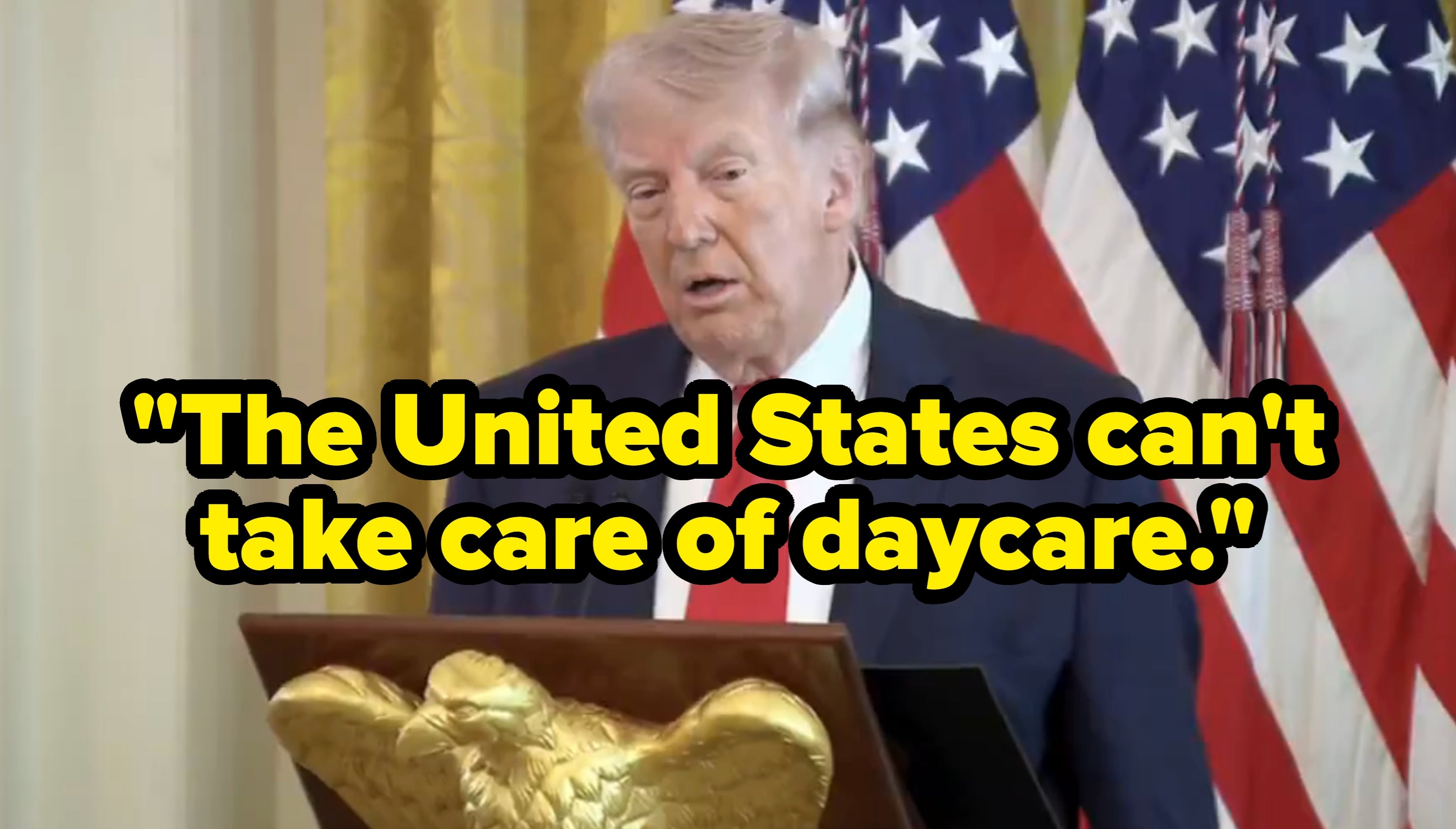 En person i dress taler ved et podium med et kongeørn-emblem, foran amerikanske flagg i en formell setting