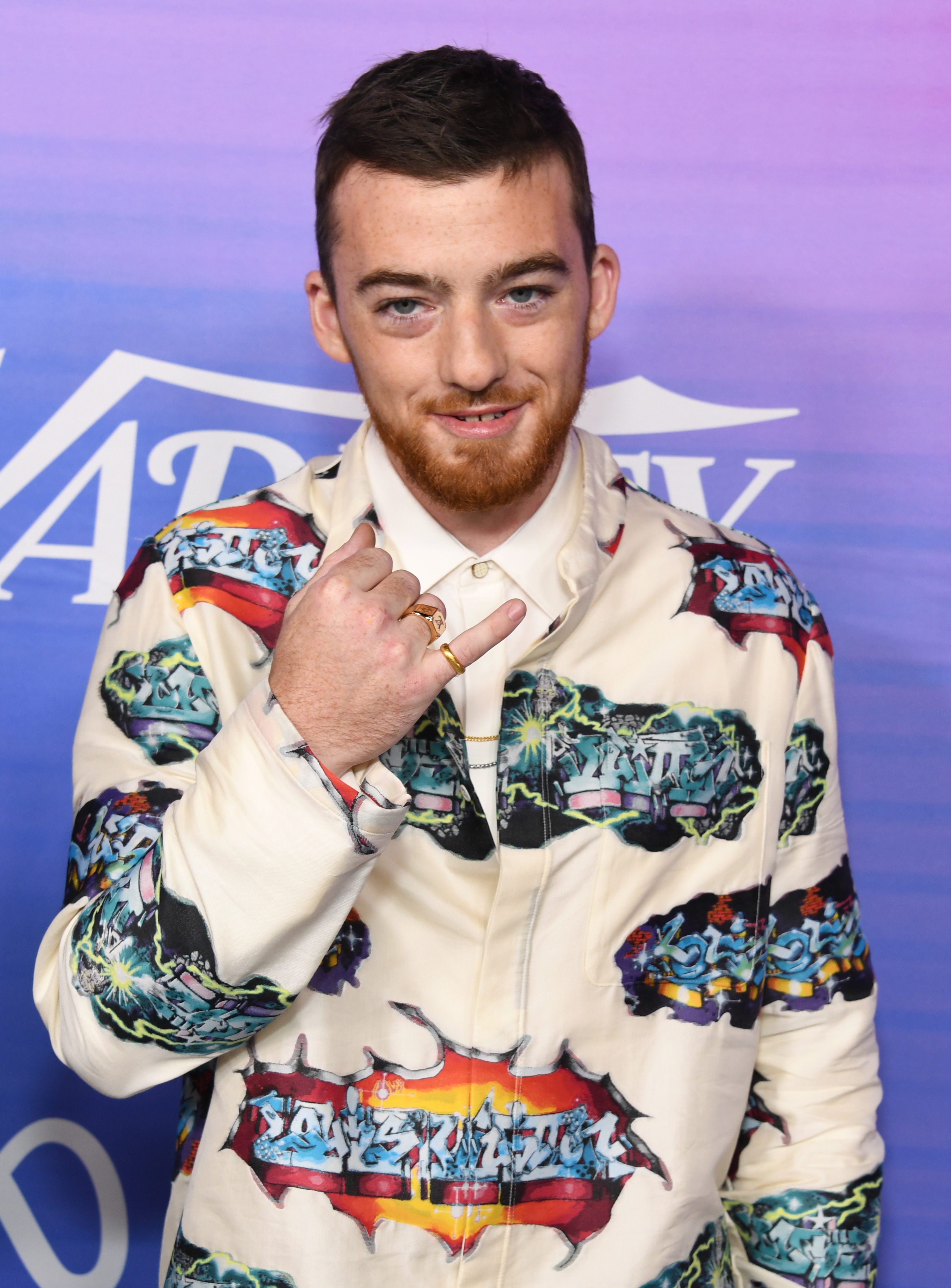 Man wearing a patterned suit with graphic print, posing with manus motion astatine a personage event