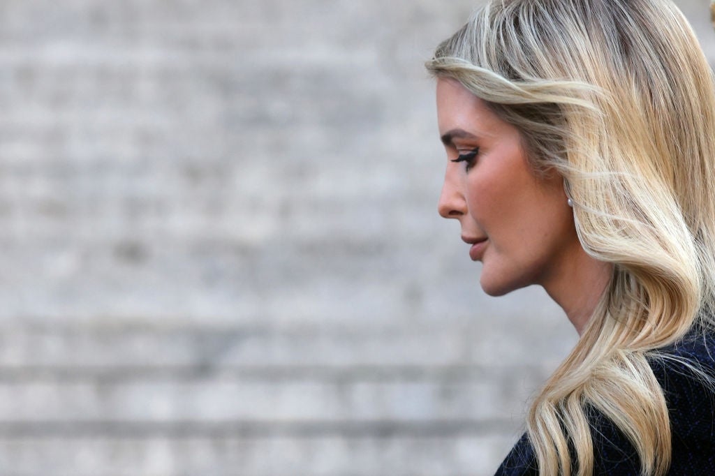 En person med langt, bølget hår som ser ned, fanget i profil mot en uskarp steinbakgrunn
