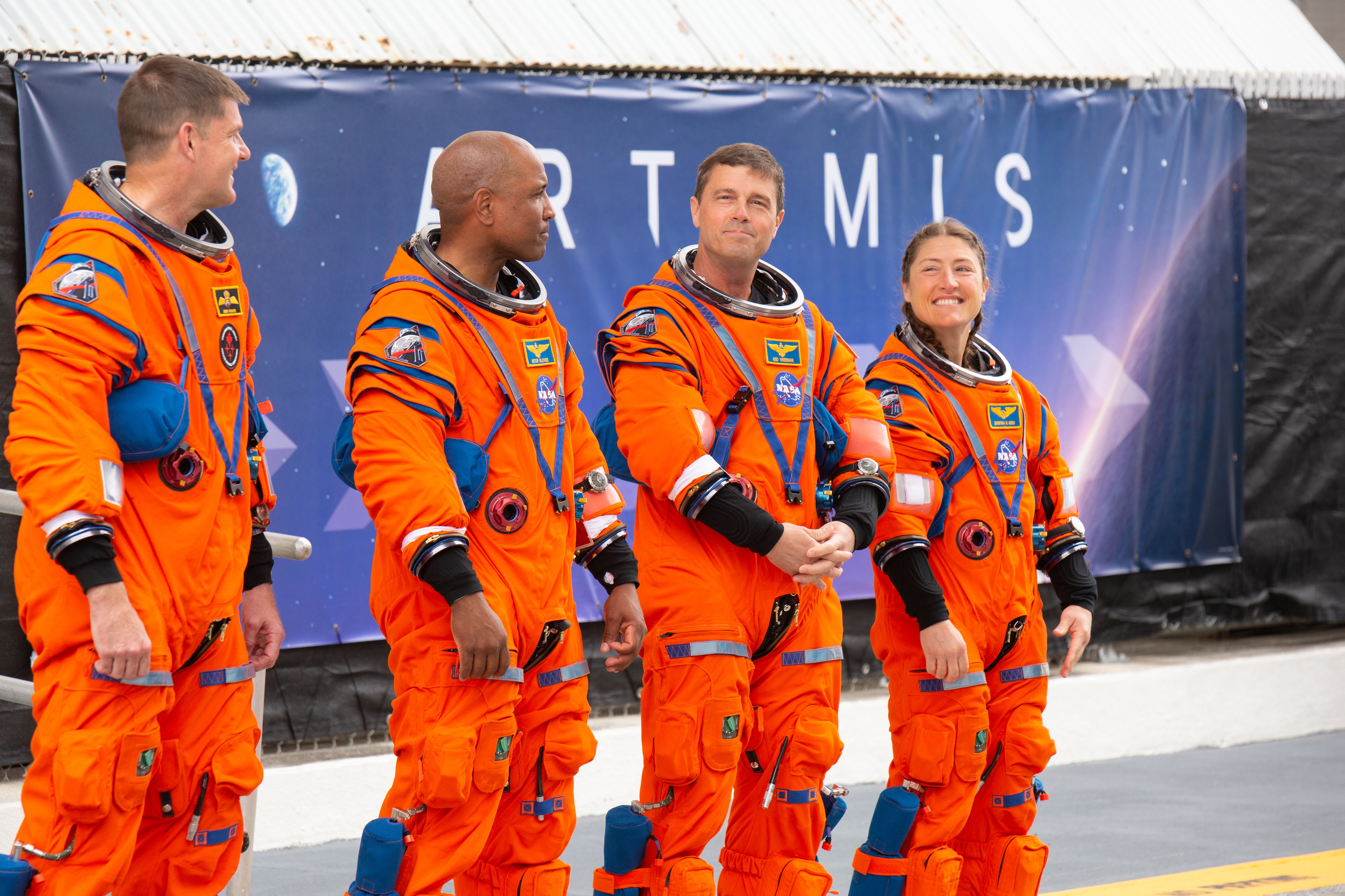 Four astronauts successful orangish abstraction suits basal successful beforehand of an Artemis ngo backdrop, preparing for a ngo event