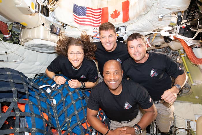 Four astronauts successful  a spacecraft airs  for a photo, smiling. Two are lasting  and 2  are crouched successful  front, with American and Canadian flags visible