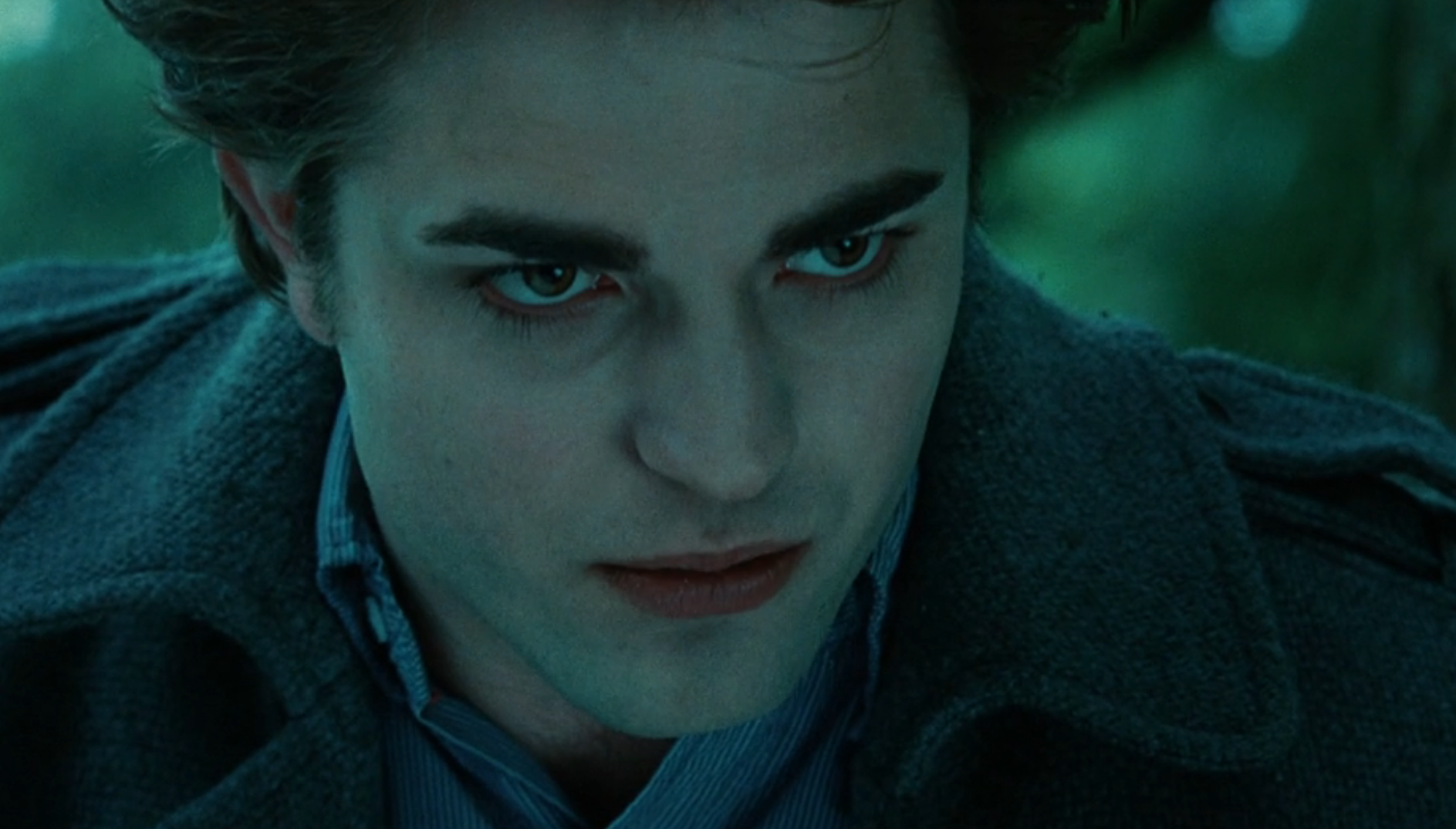 En karakter som stirrer intenst fremover, iført mørk frakk og stripet skjorte, ser ut til å være i en dramatisk scene fra en film