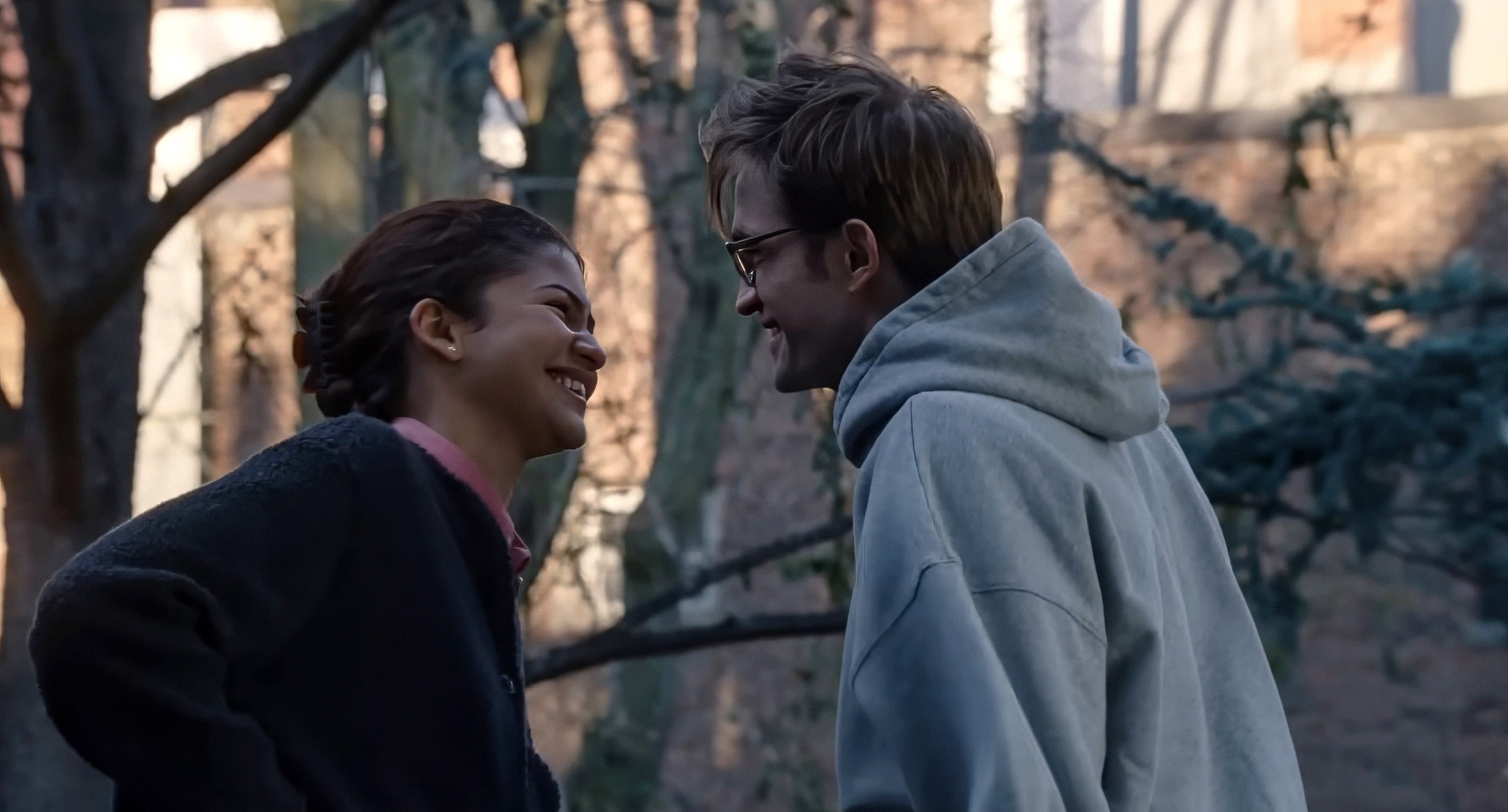 To personer som står overfor hverandre, smiler varmt i en utendørs setting