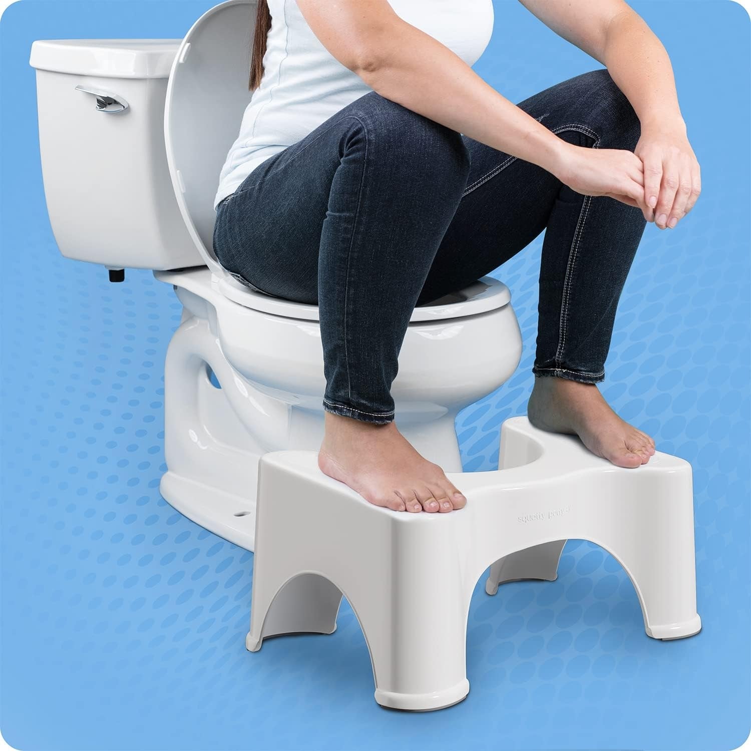 Person demonstrating a footstool for toilet use, designed to promote a natural squatting position for improved comfort and posture