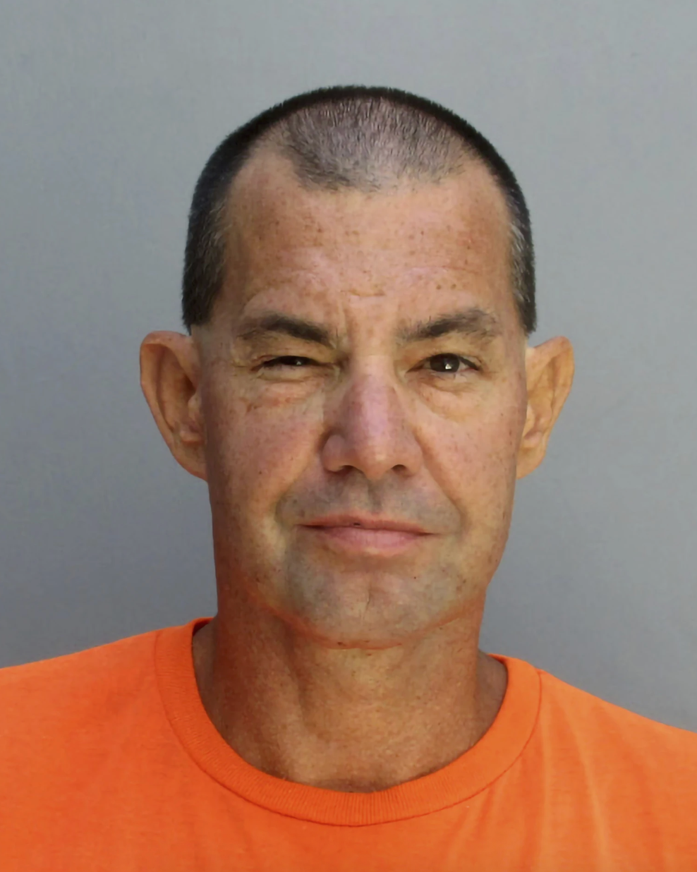 A idiosyncratic wearing an orangish garment against a plain background