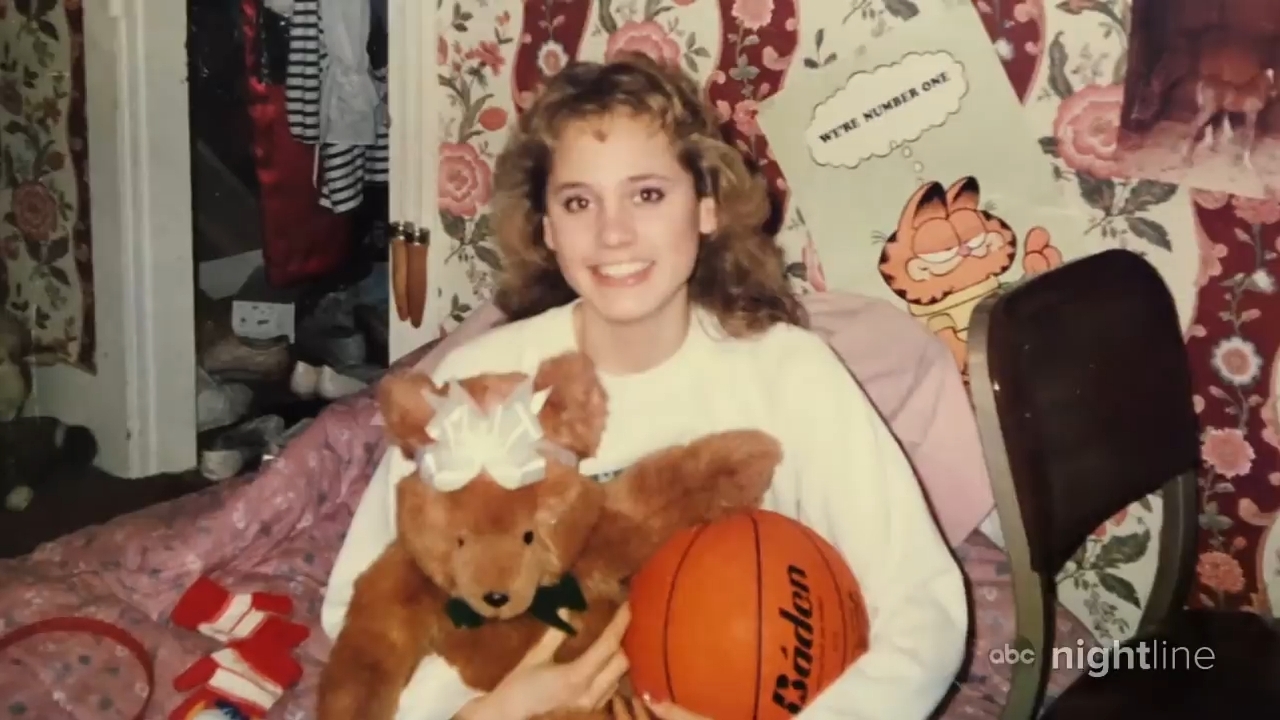 Person smiling portion holding a teddy carnivore and basketball, seated successful a chamber with Garfield decor