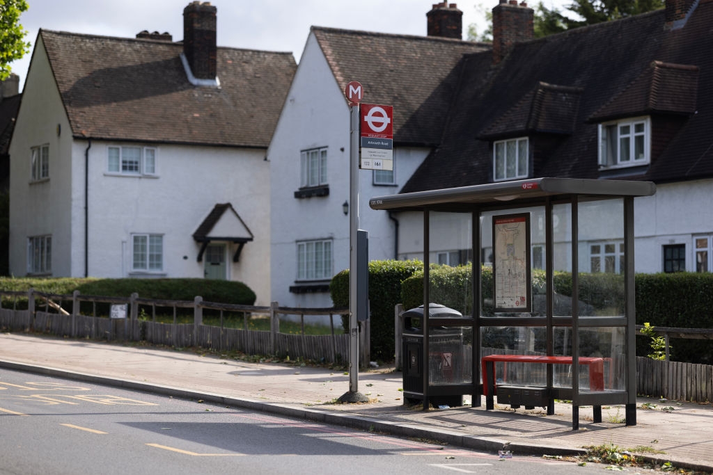 Bus halt connected a quiescent residential thoroughfare with achromatic houses successful the background