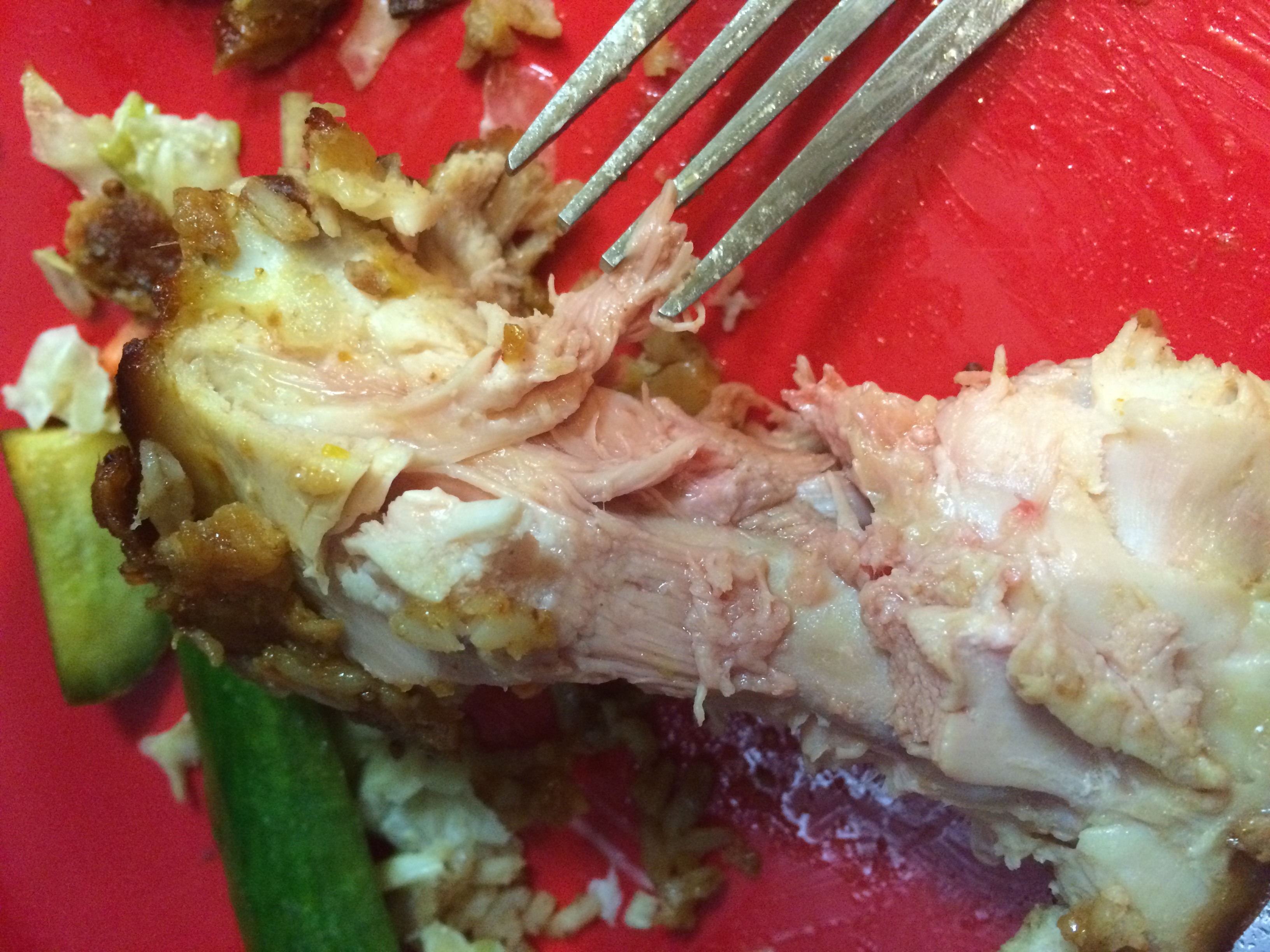 Partially eaten fried chickenhearted  portion   connected  a sheet  with a fork and immoderate   vegetables