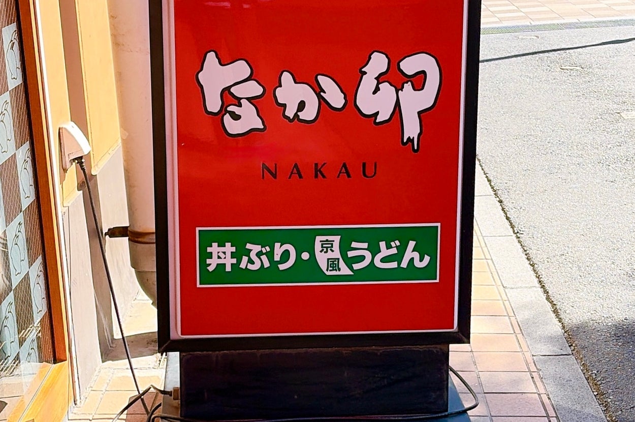 日本のチェーン店「なか卯」の看板が歩道に置かれている。