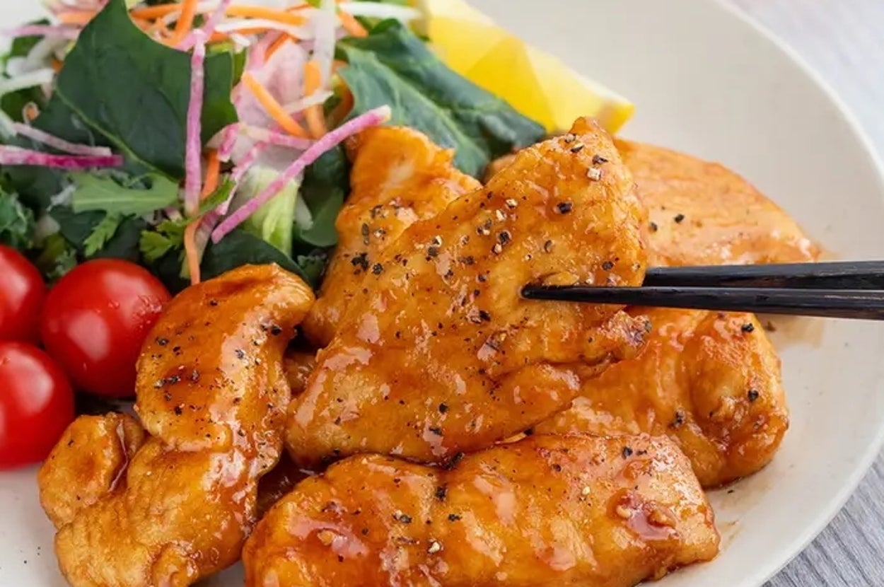 皿に盛られた照り焼きチキンとサラダの食事。トマトとレモンも添えられている。