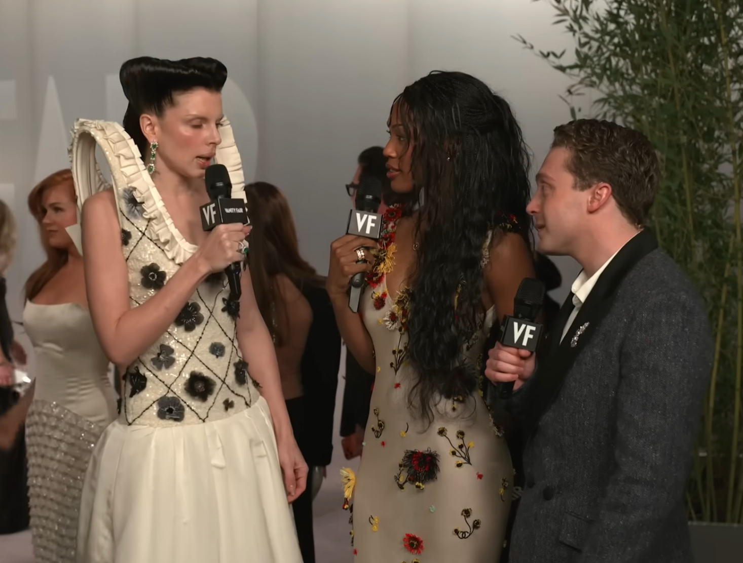 Three radical   successful  ceremonial  attire are holding microphones astatine  a personage  event. The idiosyncratic   connected  the near  wears a formal  with ruffled details