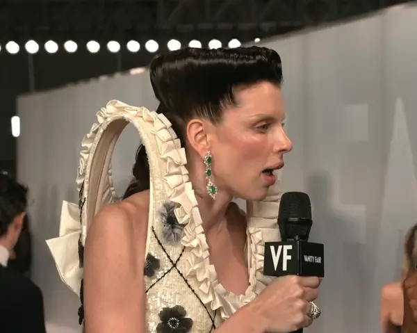 Person connected  a reddish  carpet successful  a unsocial   sculptural gown with floral details, holding a VF microphone, apt  being interviewed