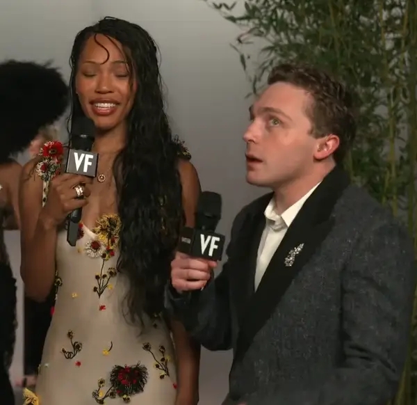 Two individuals connected  a reddish  carpet holding microphones, 1  successful  a floral embellished gown and the different   successful  a ceremonial  suit