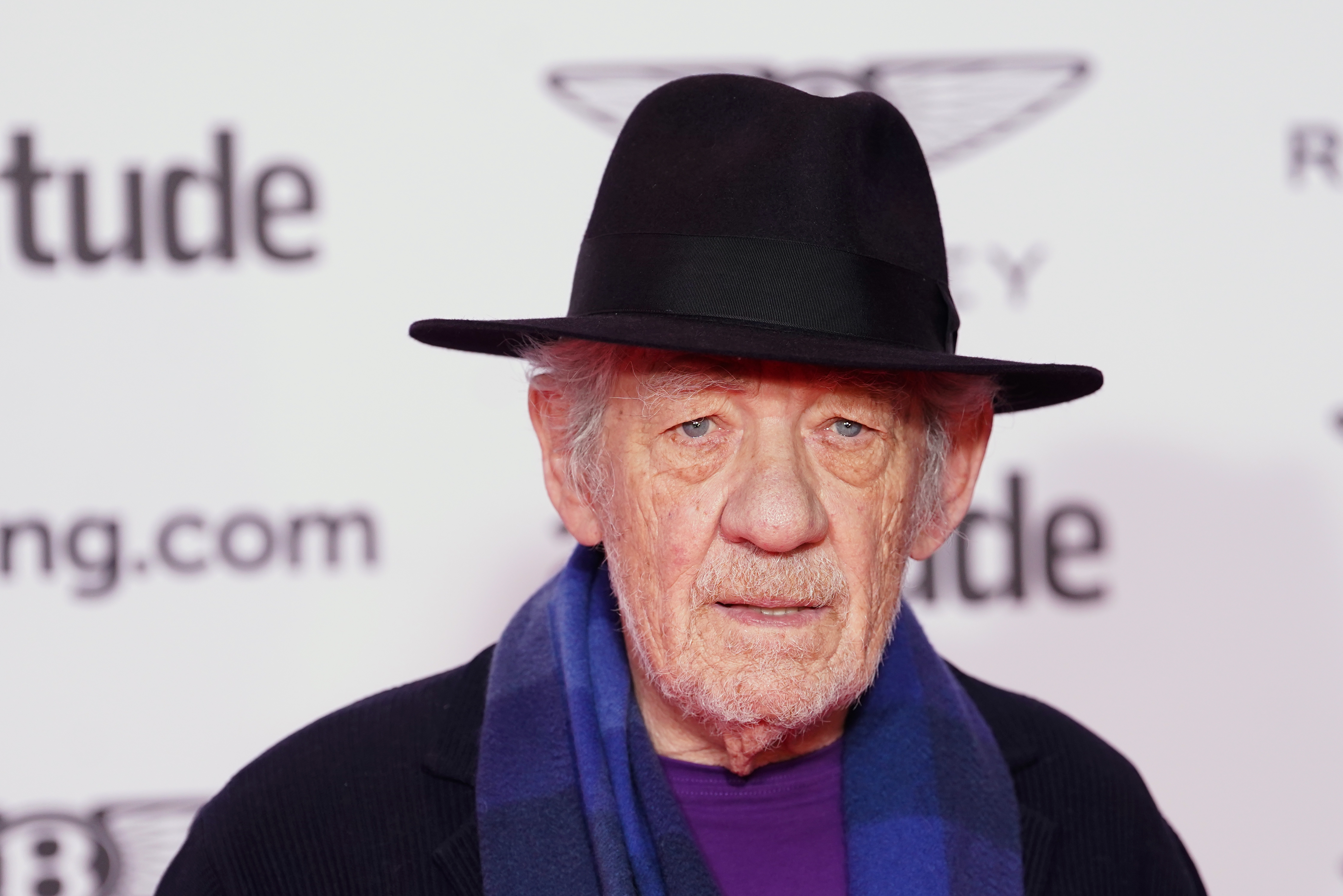 Person successful  a achromatic  chapeau  and suit   with a bluish  scarf astatine  a ceremonial  event