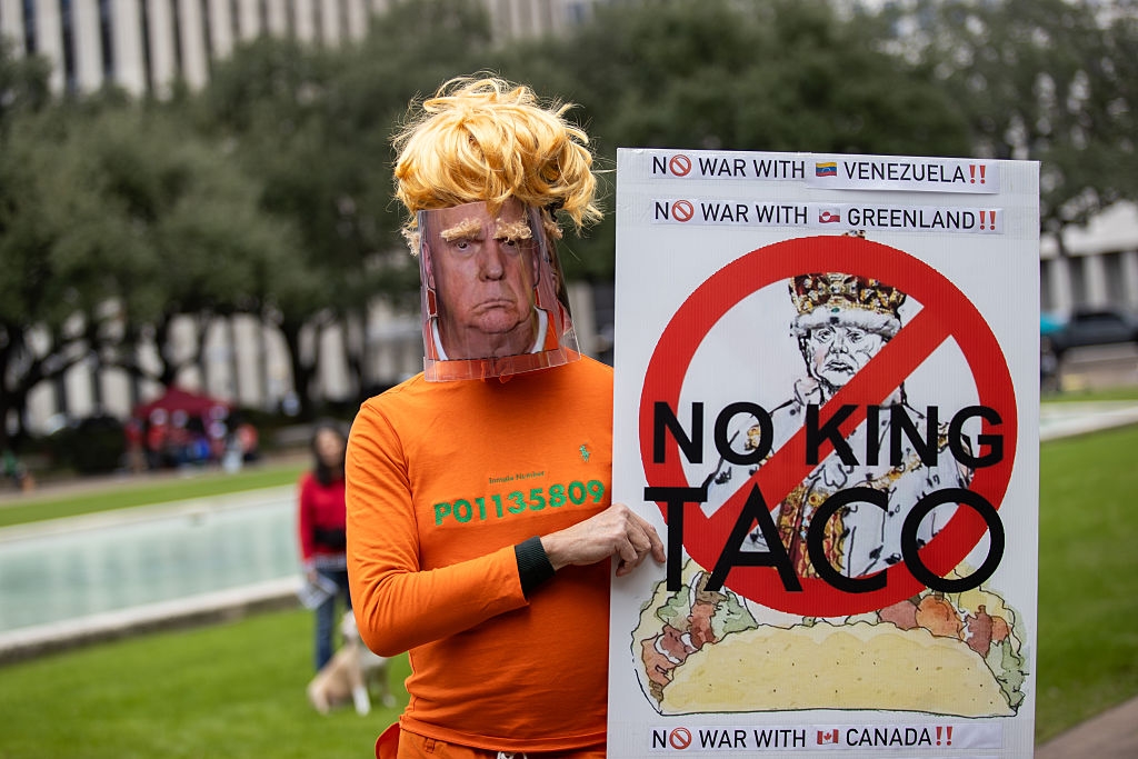Protester successful  a disguise  and wig holds a motion   against Taco Bell, referencing U.S. politics, astatine  a demonstration
