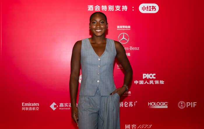 Coco Gauff successful  sleeveless vest and pants outfit, smiling connected  a reddish  carpet with logos down  them