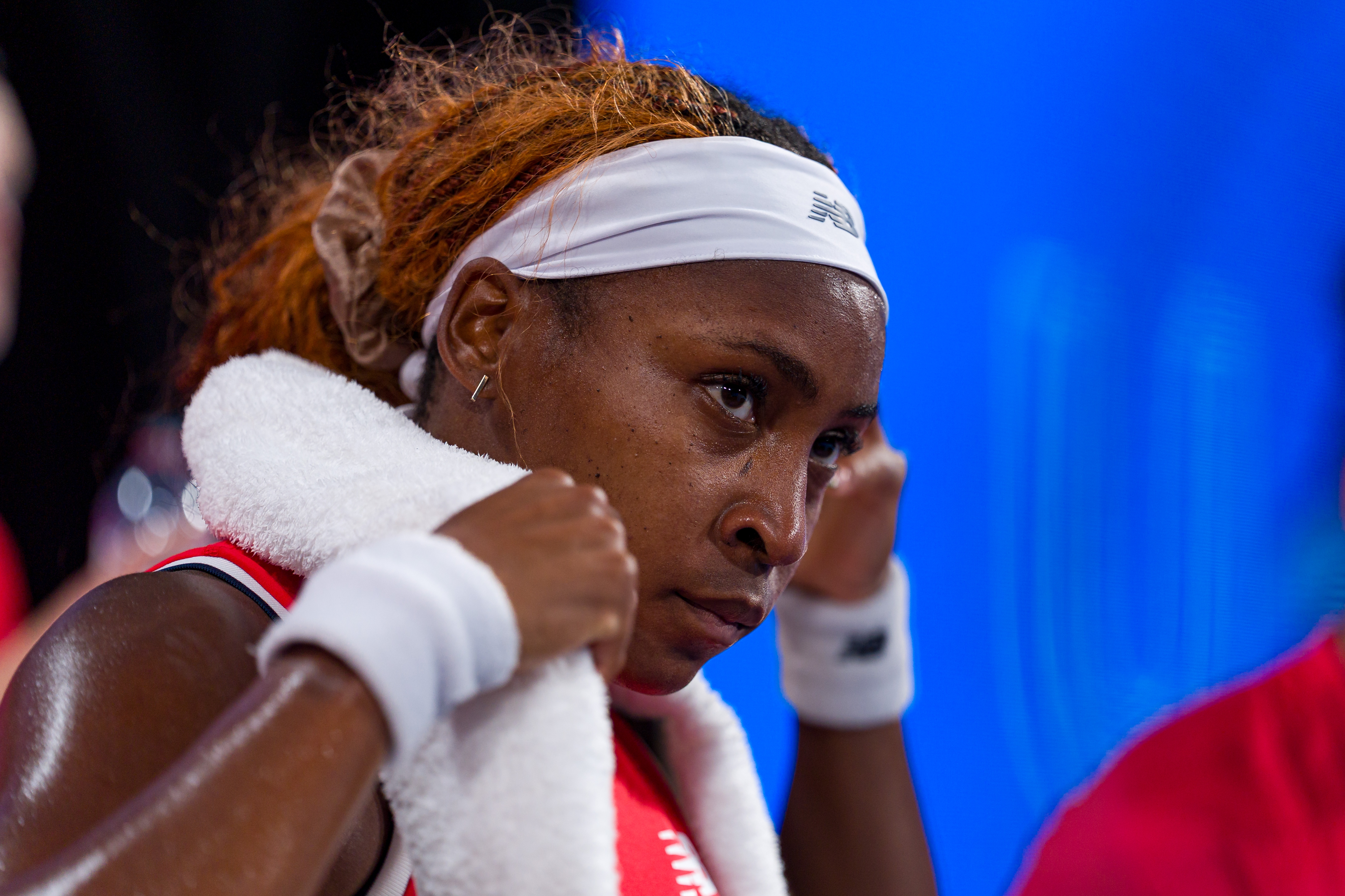 Coco Gauff with a headband and towel astir   the neck, focused during a match