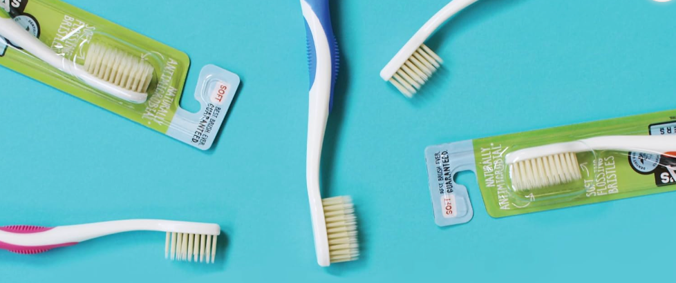 Several manual toothbrushes and packaged brush heads are spread out on a flat surface