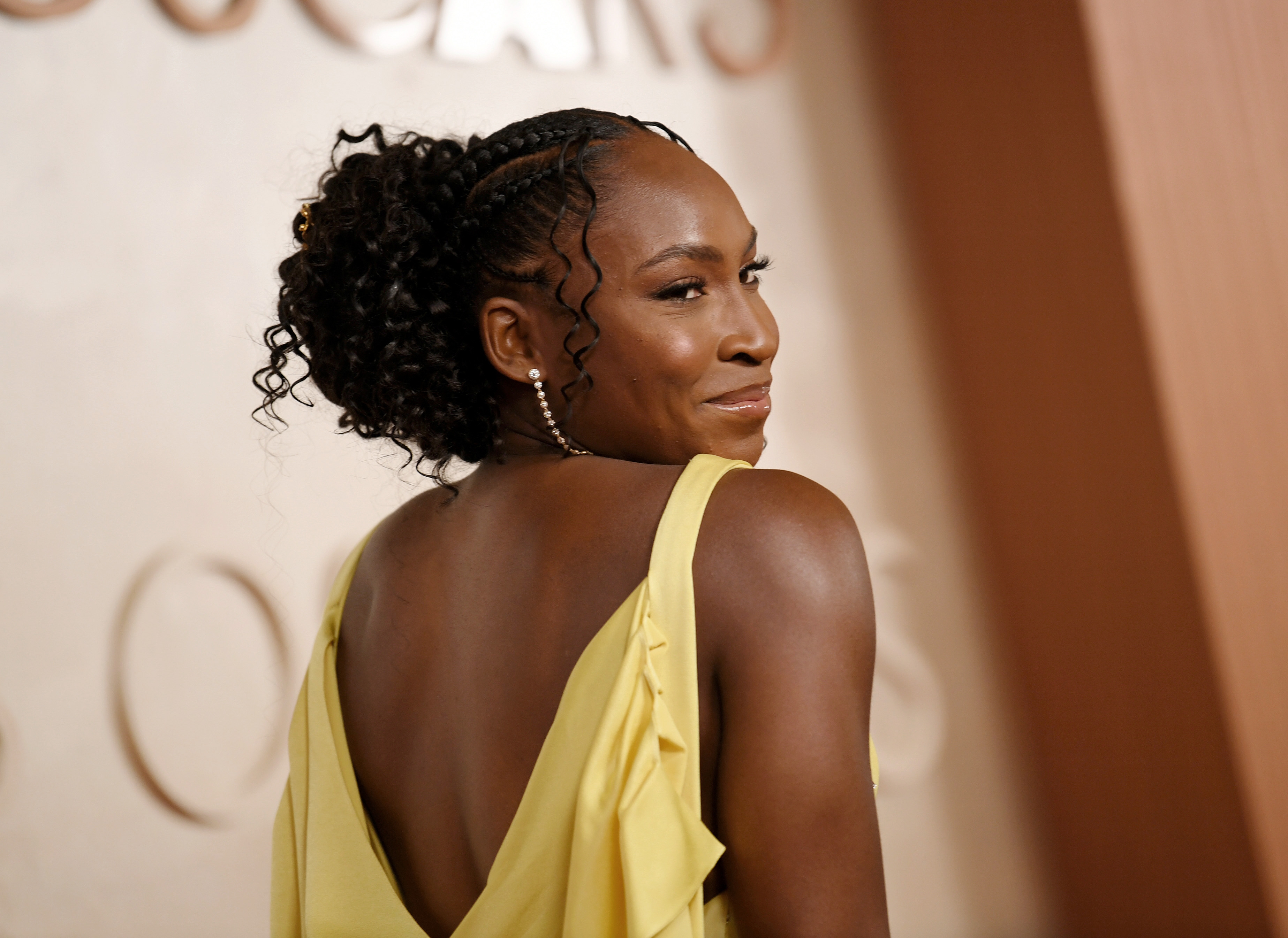 Coco Gauff with styled hairsbreadth  looks implicit    their shoulder, wearing an elegant gown with a heavy  back, astatine  a ceremonial  lawsuit   backdrop