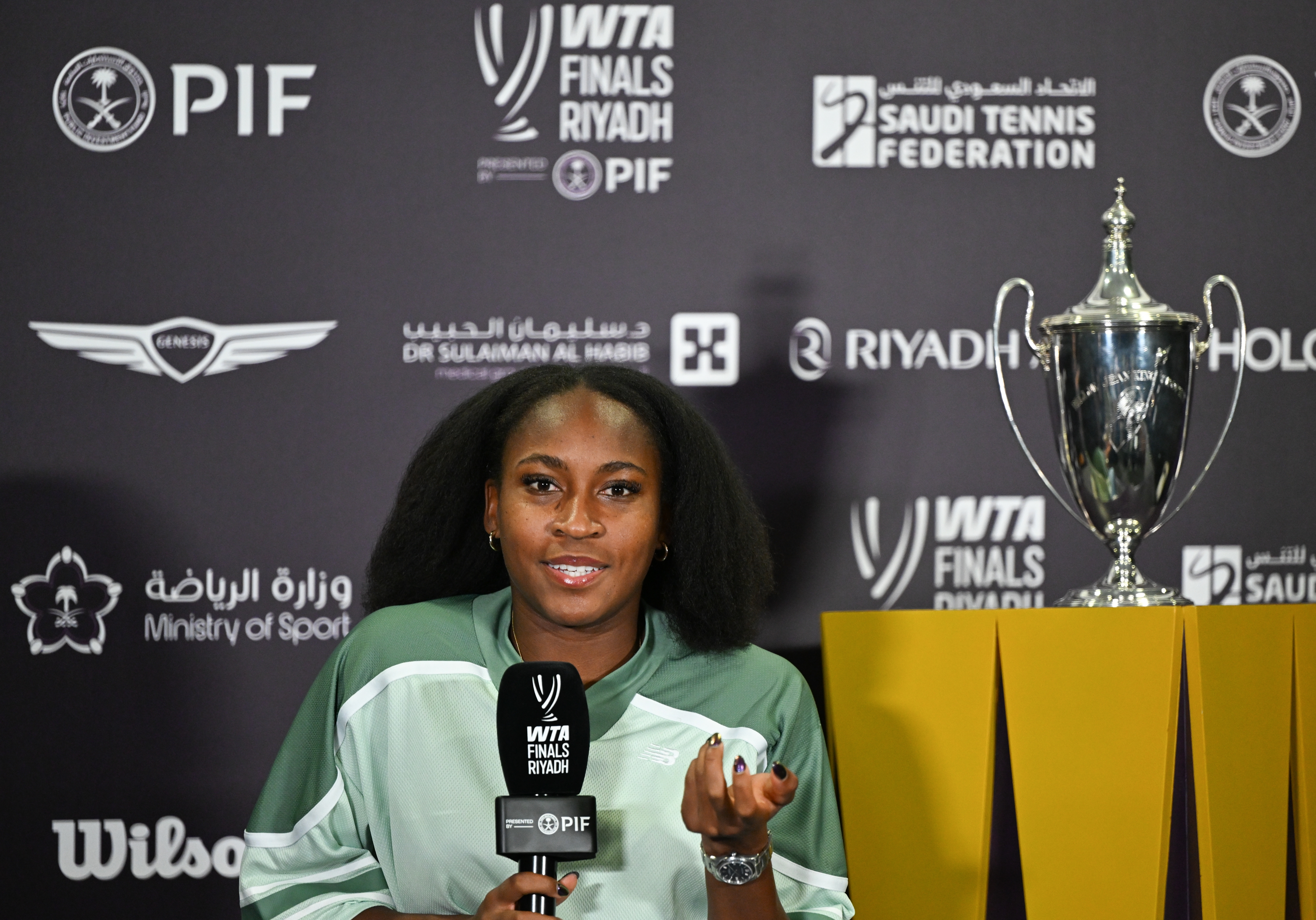 Coco Gauff speaking astatine  a property   lawsuit   for WTA Finals Riyadh, with a trophy displayed beside them