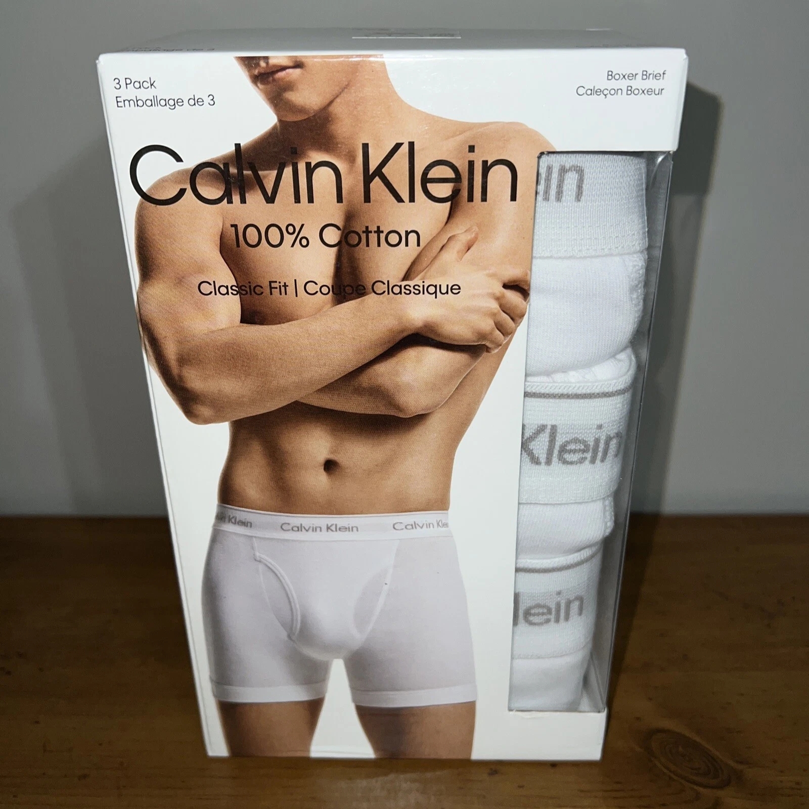 Box of Calvin Klein men's boxer briefs, labeled 100% cotton, classical  fit, successful  a 3-pack. Packaging shows exemplary  wearing the briefs