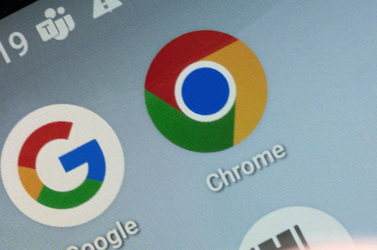 スマートフォン画面にGoogle Chromeなどのアプリアイコンが表示されている。指が画面を操作している。