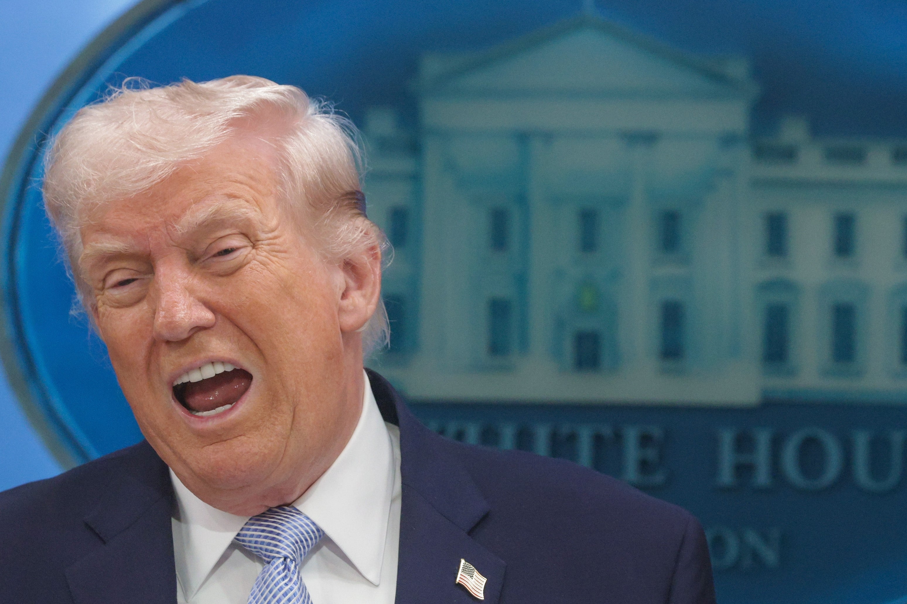 En person som snakker animert ved et podium med et bakteppe i Det hvite hus bak seg