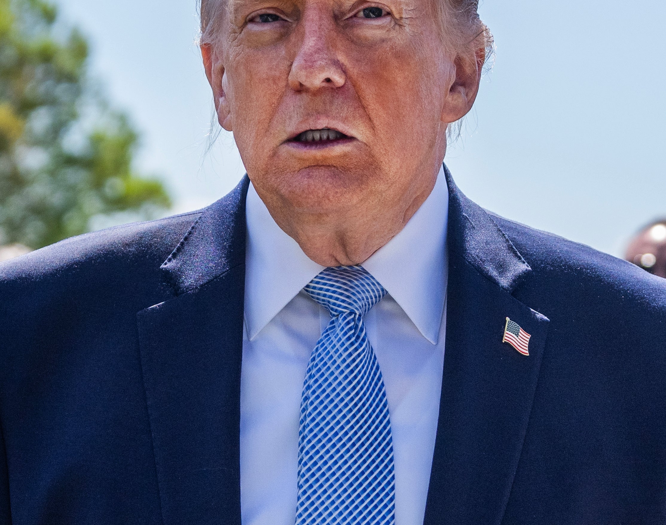 En person i dress og slips står utenfor med Washington-monumentet i bakgrunnen, omgitt av en folkemengde