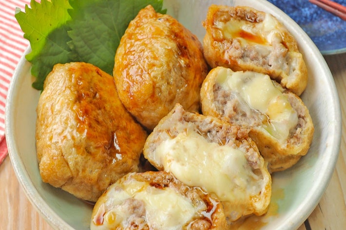 皿に盛られた肉とチーズ入りのいなり寿司。背景に箸と植物が見える。