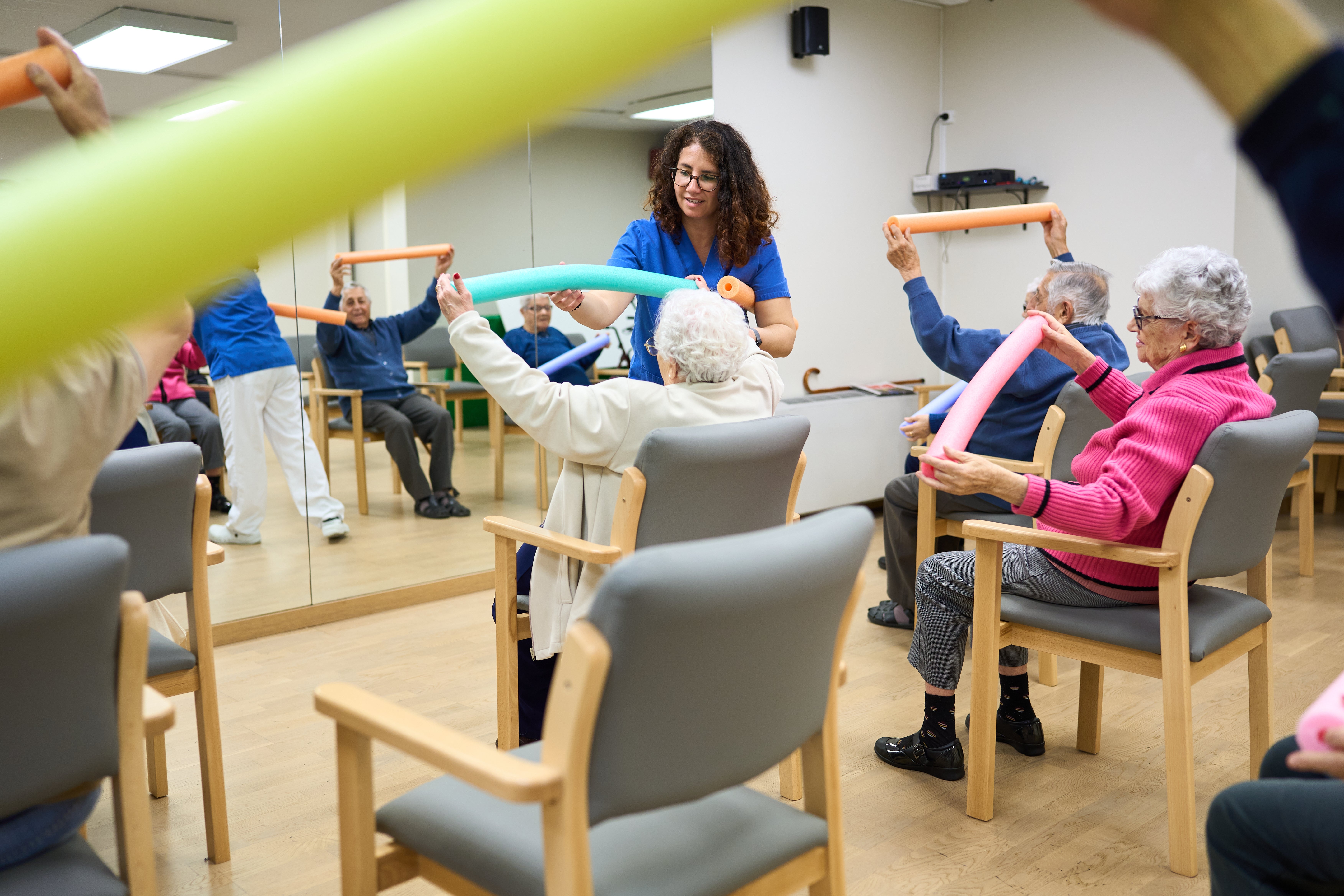 Seniors successful  a radical  workout  people  assistance   foam tubes portion    an teacher  guides them, promoting carnal   enactment   and societal  interaction