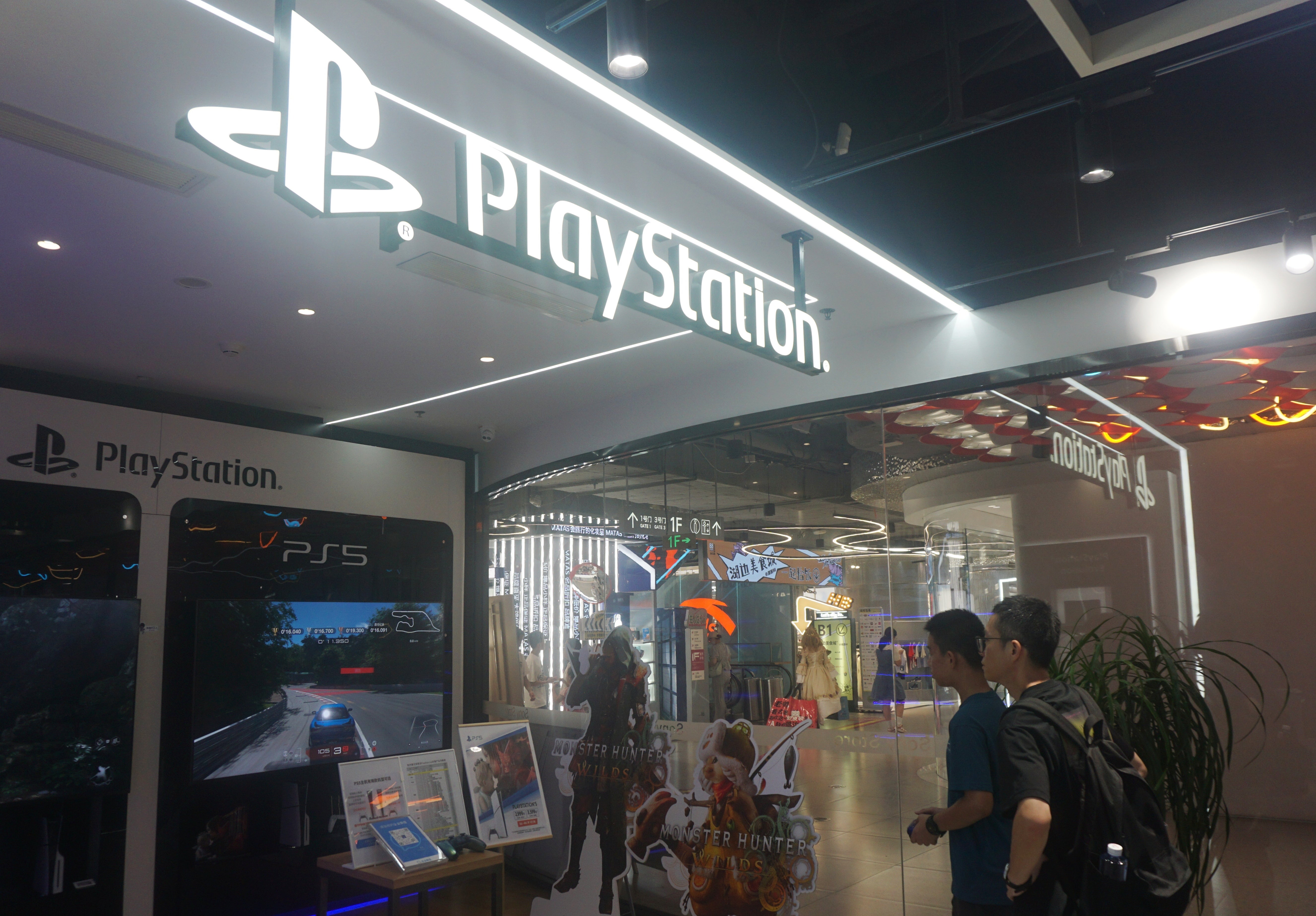 People looking astatine  a PlayStation store   show  with PS5 games, integer  signage, and branded decor wrong  a modern   buying  center
