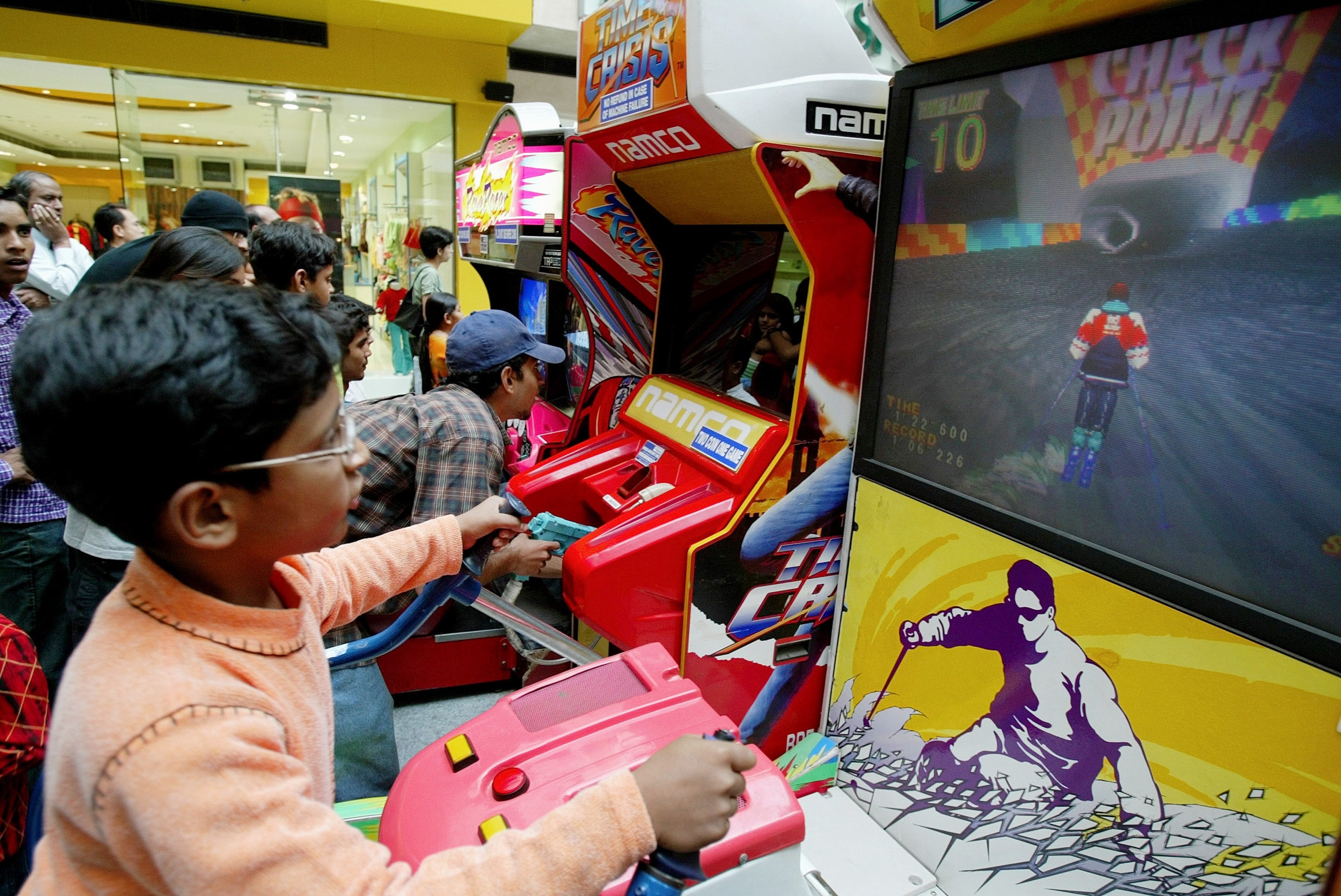 Child plays a motorcycle racing arcade crippled  successful  a bustling arcade with onlookers nearby