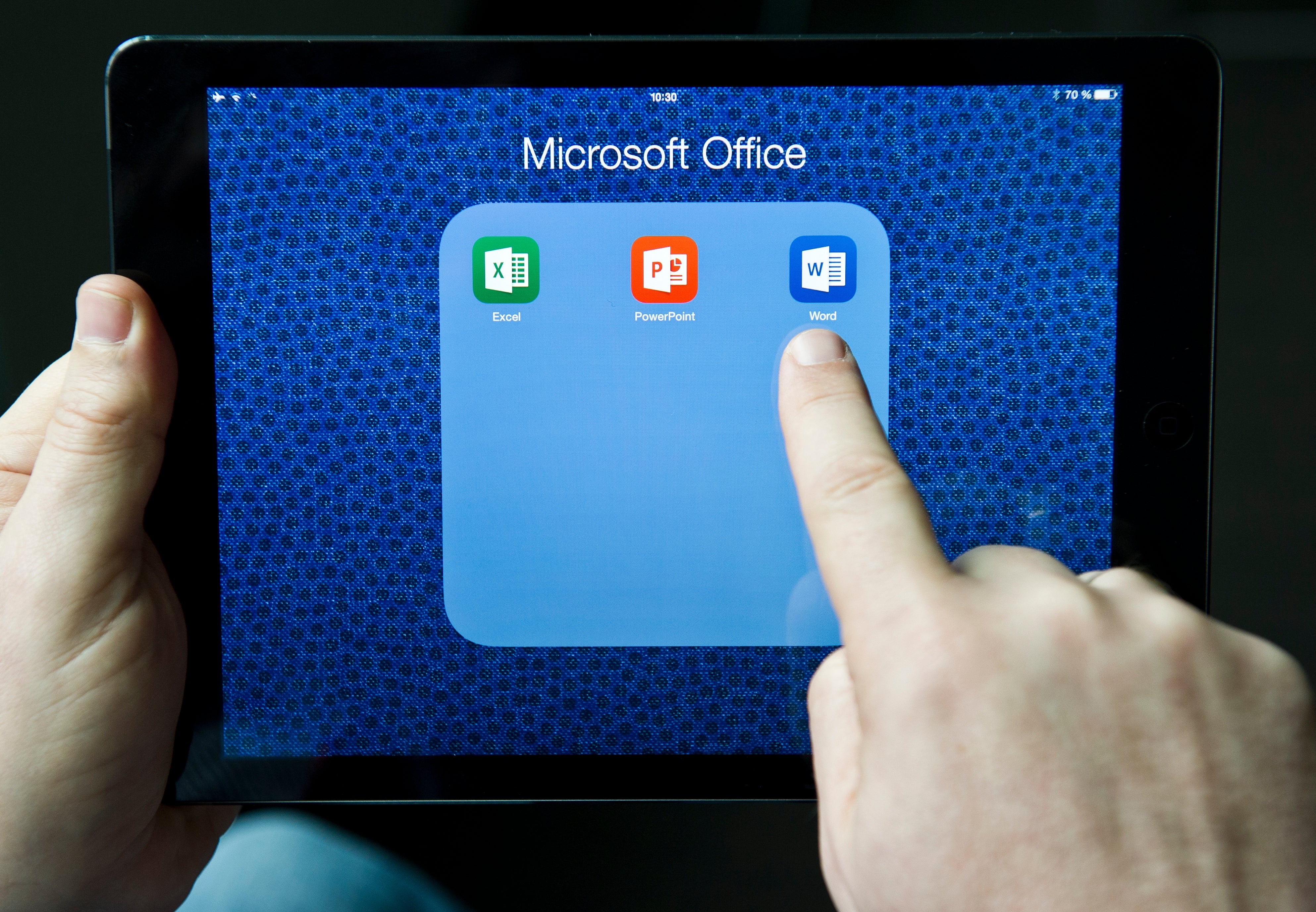 Person tapping Microsoft Word icon connected  a tablet surface  with Excel, PowerPoint, and Word apps visible