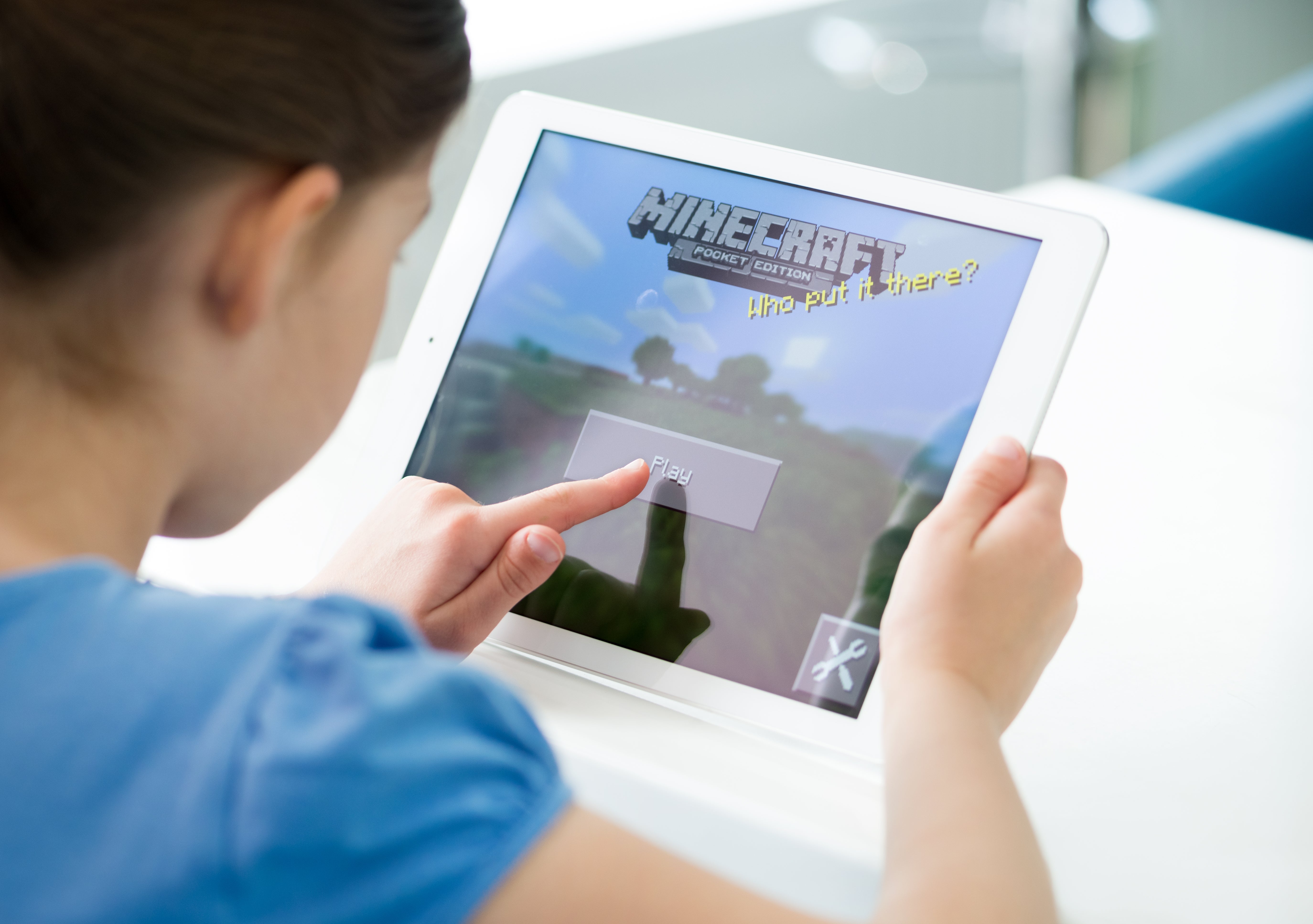Child playing Minecraft connected  a tablet, navigating the game's menu