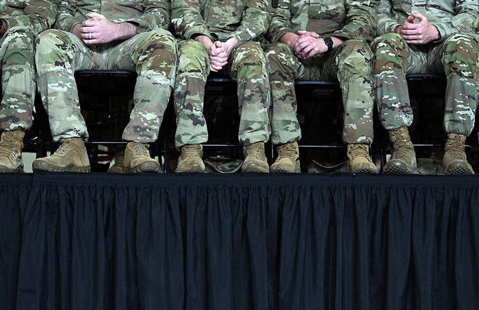 A enactment      of radical   successful  camouflage uniforms and boots beryllium   connected  a signifier    with their hands clasped, legs disposable   nether  a achromatic  curtain