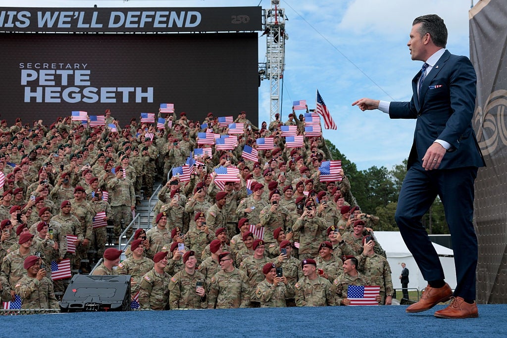 A antheral successful a suit gestures towards a ample radical of soldiers successful azygous holding American flags during an outdoor event