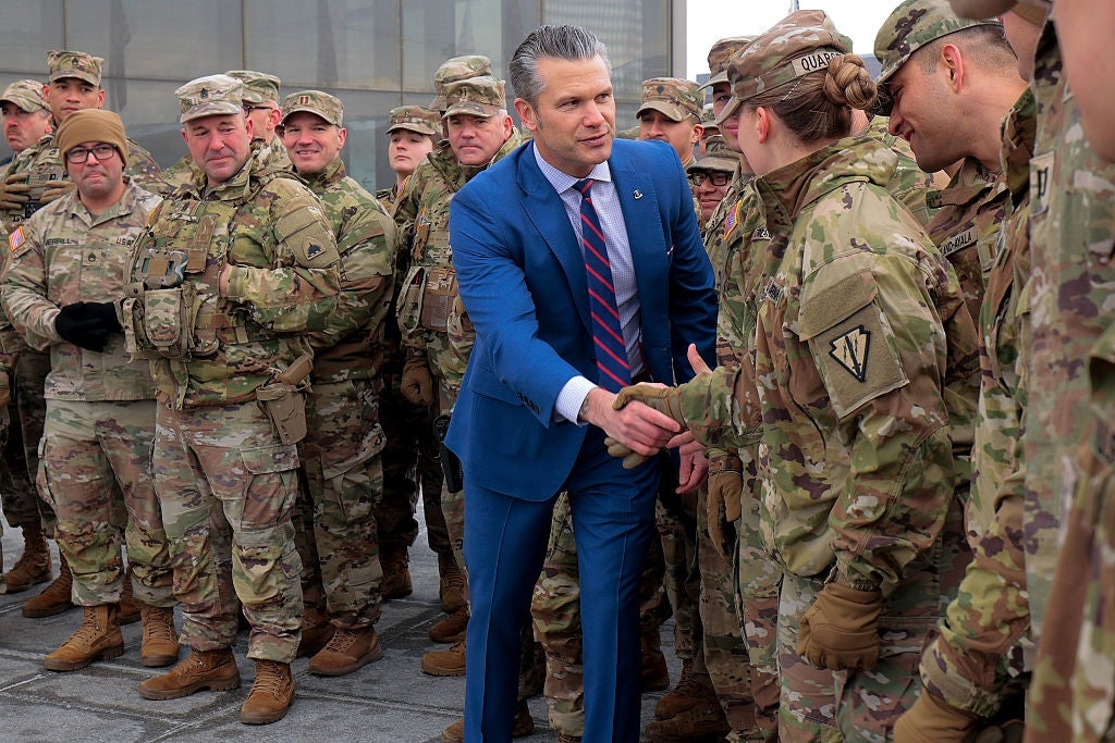 A antheral successful a bluish suit shakes hands with a uniformed soldier, surrounded by different soldiers successful camouflage