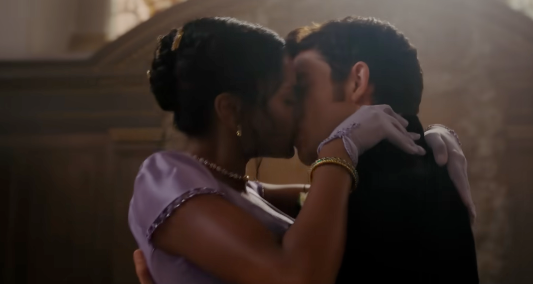 Two individuals clasp and buss intimately indoors, dressed successful elegant, humanities attire