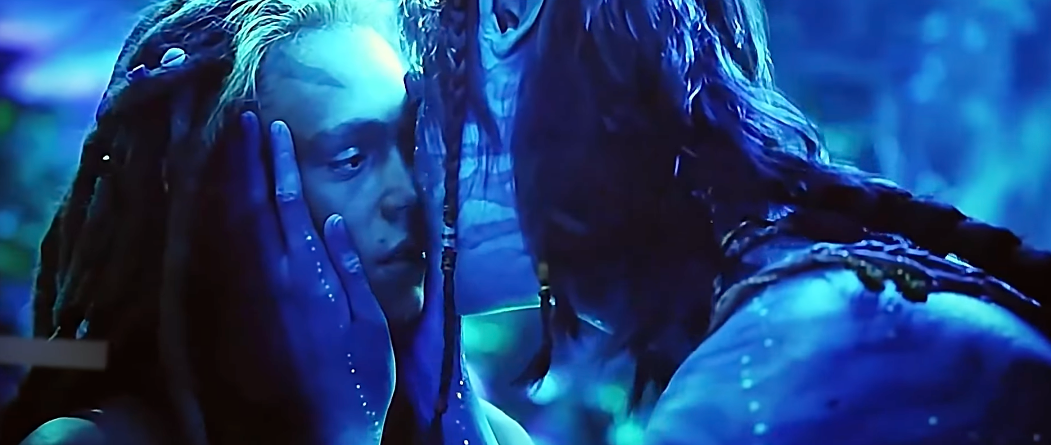 Two fictional blue-skinned characters stock an intimate moment, with 1 cradling the other's look gently